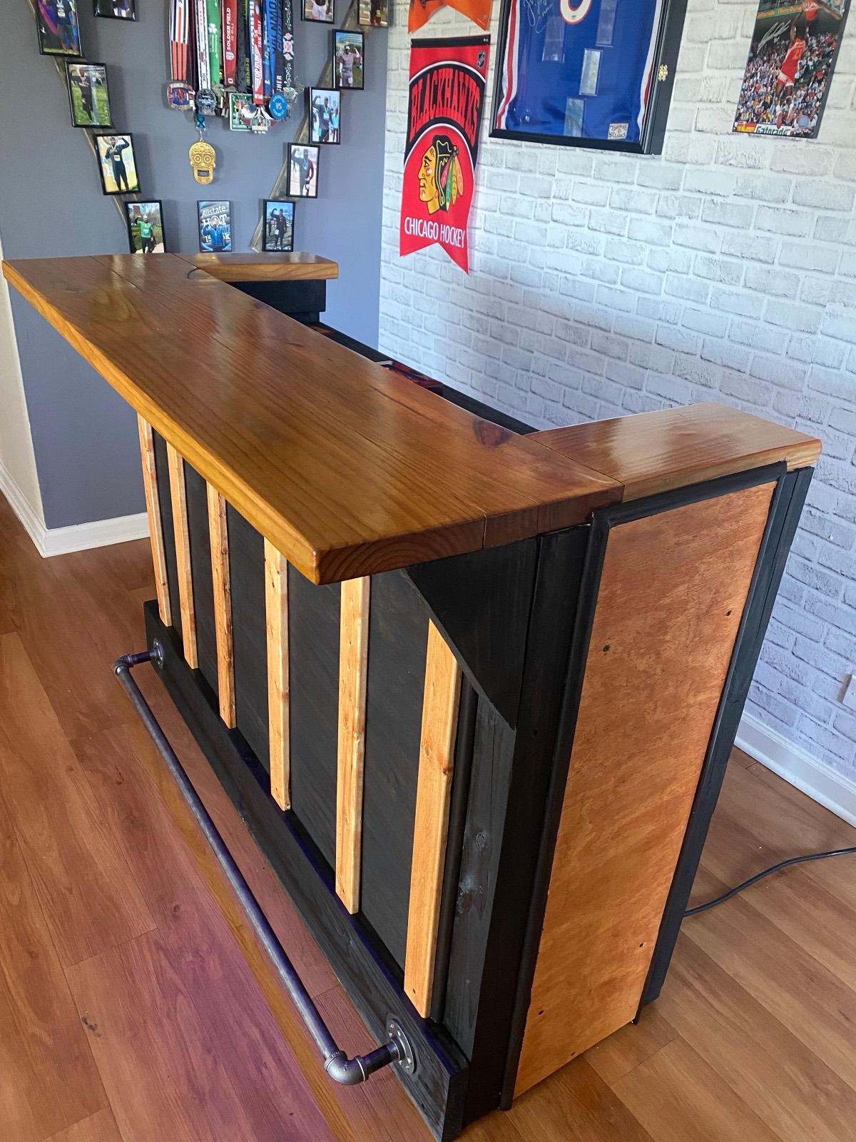 Custom home bar with a finished wood top, foot rail and panelled front